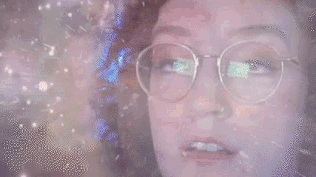 a close up of a woman wearing glasses and a nose ring .