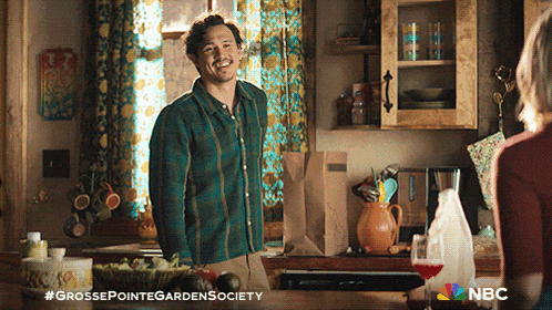 a man in a plaid shirt stands in a kitchen next to a woman and a bottle of milk