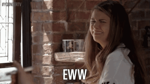 a woman is sitting in front of a brick wall making a funny face and says eww .
