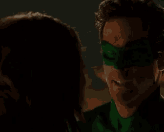 a man wearing a green mask is standing next to a woman .