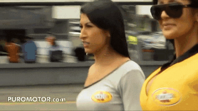 two women standing next to each other with puromotor.com on the bottom