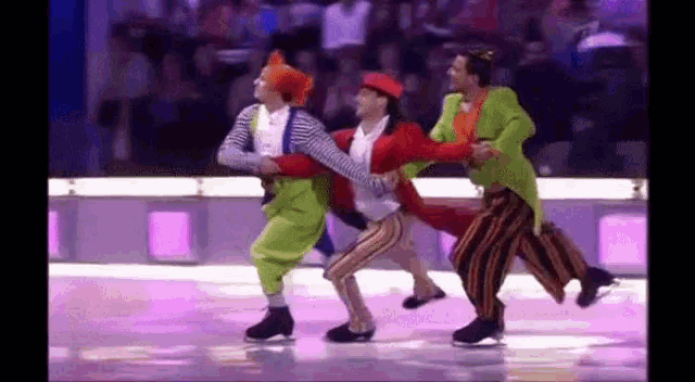 a group of clowns are dancing on the ice .