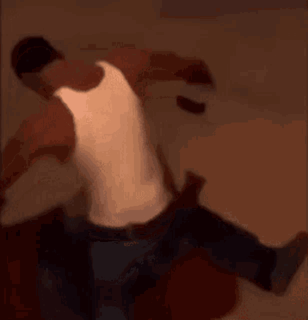 a man in a white tank top is sitting on another man 's back .