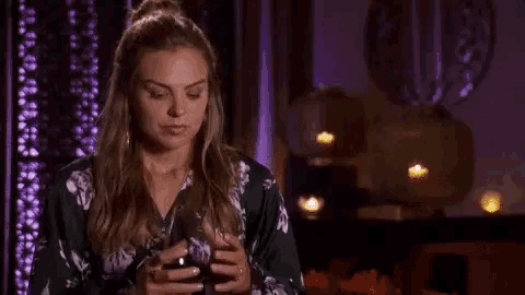 a woman is drinking a glass of red wine in a room with candles .