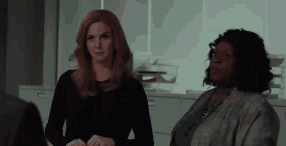 two women are sitting next to each other in a room and looking at each other .
