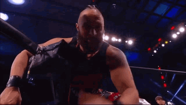 a man with a beard is standing in a wrestling ring with a referee behind him .