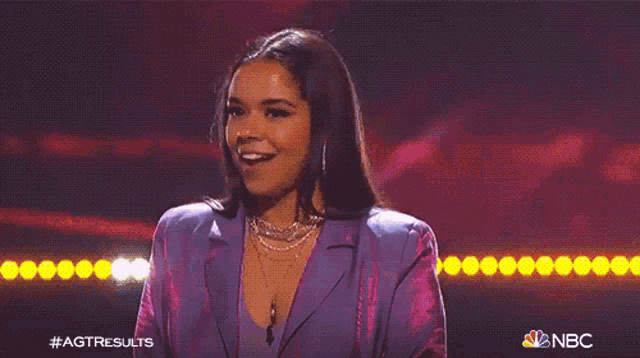 a woman in a purple suit is smiling on stage .