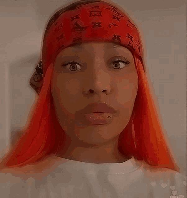 a woman with orange hair wearing a red louis vuitton headband looks surprised
