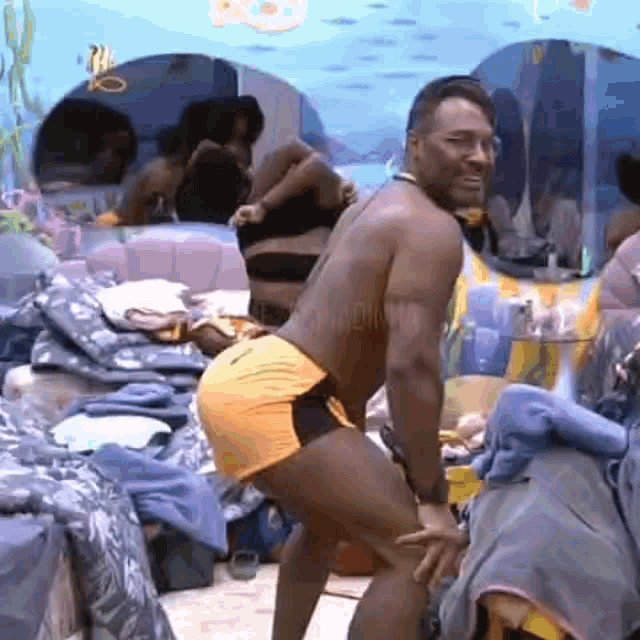 a man in a bathing suit is dancing in a room with a woman behind him .