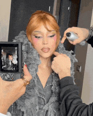 a person taking a picture of a woman 's face with a camera that says ' nikon ' on it