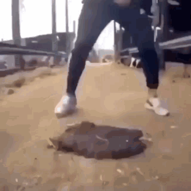 a man is standing on a manhole cover in the dirt .
