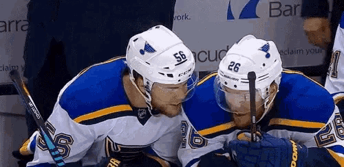 two hockey players are looking at each other and one has the number 56 on his helmet