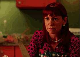 a woman with red hair is wearing a plaid shirt and pearls