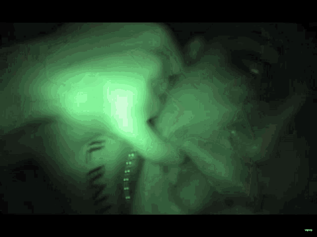 a green light is shining on a person 's face in the dark .
