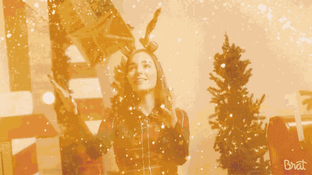 a woman wearing a reindeer headband is holding a christmas present in her hand
