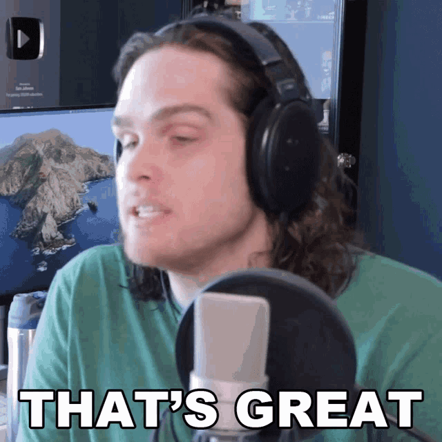 a man wearing headphones stands in front of a microphone and says that 's great