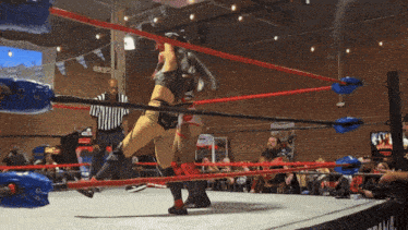 two women are wrestling in a wrestling ring with a referee watching