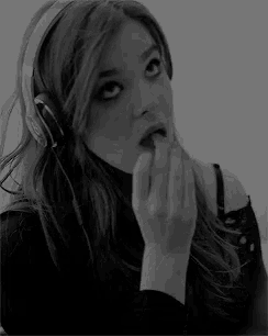 a black and white photo of a woman wearing headphones and making a funny face .