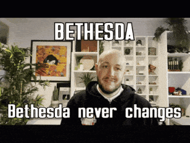 a man in a bethesda hoodie stands in front of a bookcase