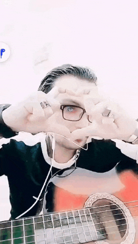 a man wearing glasses and headphones making a heart with his hands