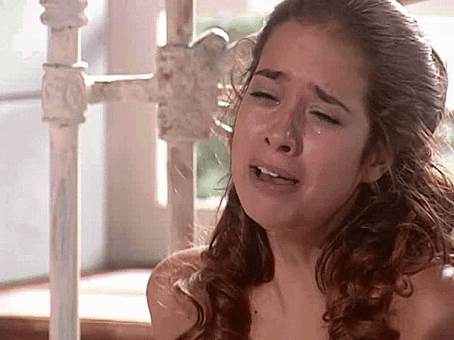 a woman is crying with a tear running down her face while sitting on a bed .