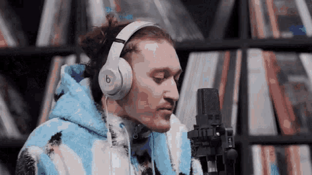 a man wearing headphones is singing into a microphone in a library .