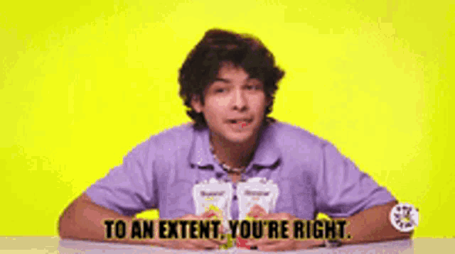 a man sitting at a table with the words " to an extent you 're right " on the screen