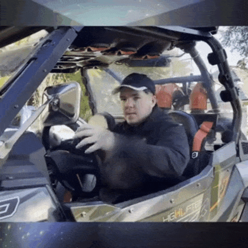 a man in a black hat is driving a vehicle that says highlights