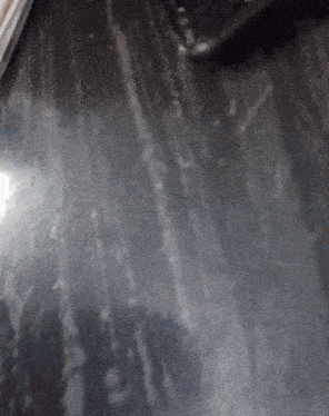 a close up of a black surface with a few spots on it
