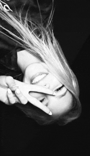 a woman is smiling and making a peace sign with her hands