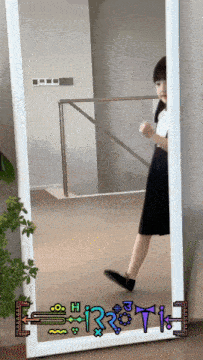 a girl is standing in front of a mirror with a drawing of a sword and the letter h on it