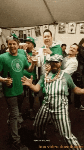 a group of men in green and white striped overalls are dancing in a tent