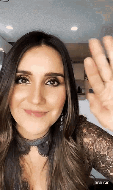 a woman in a lace top is smiling and waving