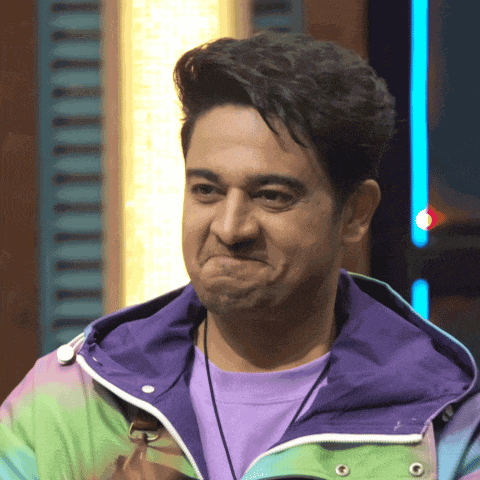 a man wearing a tie dye jacket and a purple shirt makes a funny face