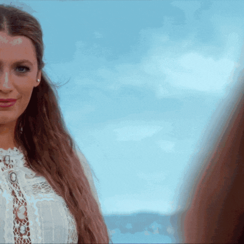 a woman in a white lace top looks at the camera