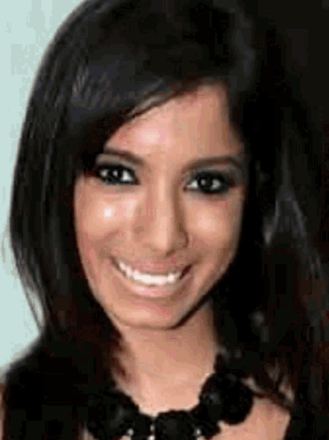 a close up of a woman 's face with a black necklace and smiling .