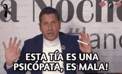a man in a suit is holding a cigarette in front of a sign that says esta tia es una psicopata , es mala