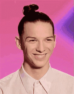 a man with a bun on his head and a white shirt is smiling .