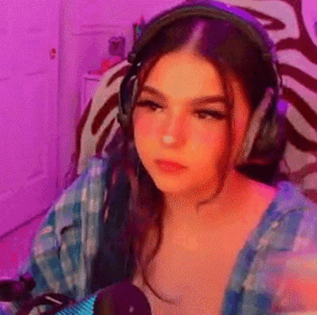 a woman wearing headphones is sitting in front of a microphone in a room .