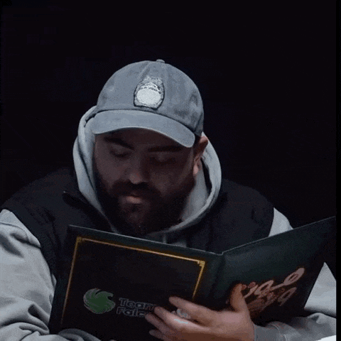 a man wearing a grey hat is reading a book titled team palace
