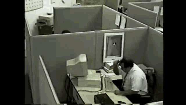 a man is sitting at a desk in front of a computer monitor .