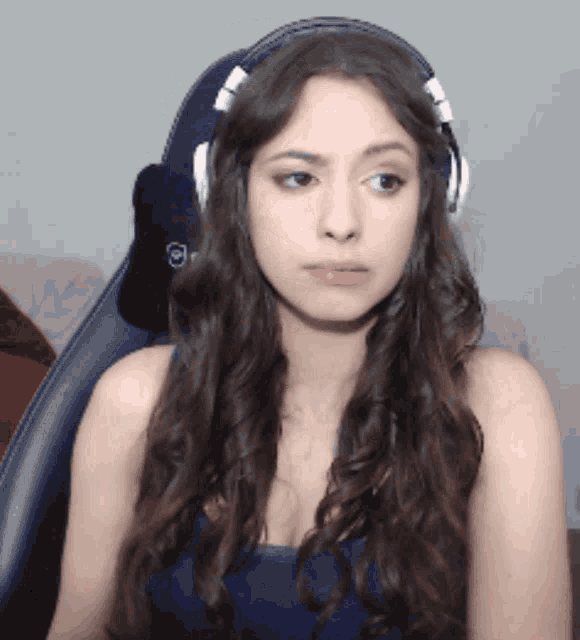 a woman wearing headphones is sitting in a chair and looking at something