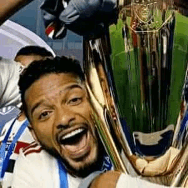 a man is holding a trophy in his hands and smiling with his mouth open .