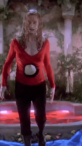 a woman in a red top and black pants stands in front of a pool