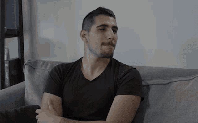 a man in a black shirt is sitting on a couch