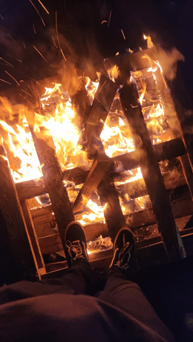 a person standing in front of a burning wooden structure