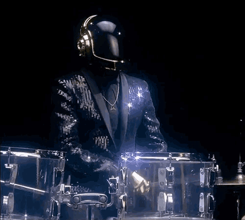 a man in a sequined suit is playing a drum set