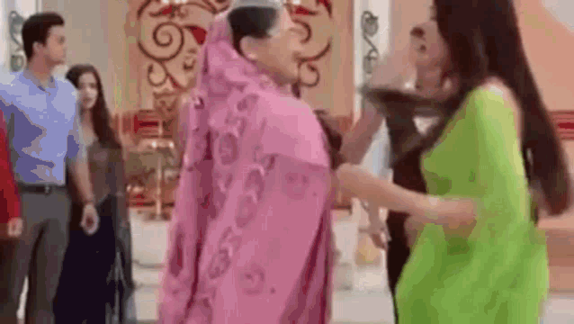 a woman in a pink dress is standing next to a woman in a green dress .