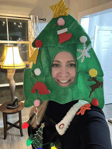a woman is wearing a christmas tree hat and smiling