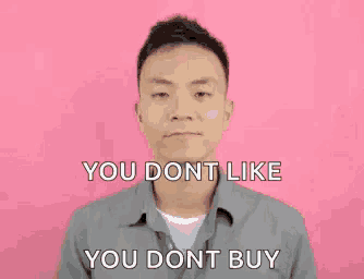 a man is standing in front of a pink background and making a funny face .